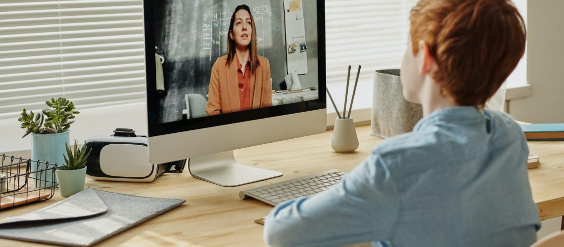 a boy in front of computer talking to his teacher